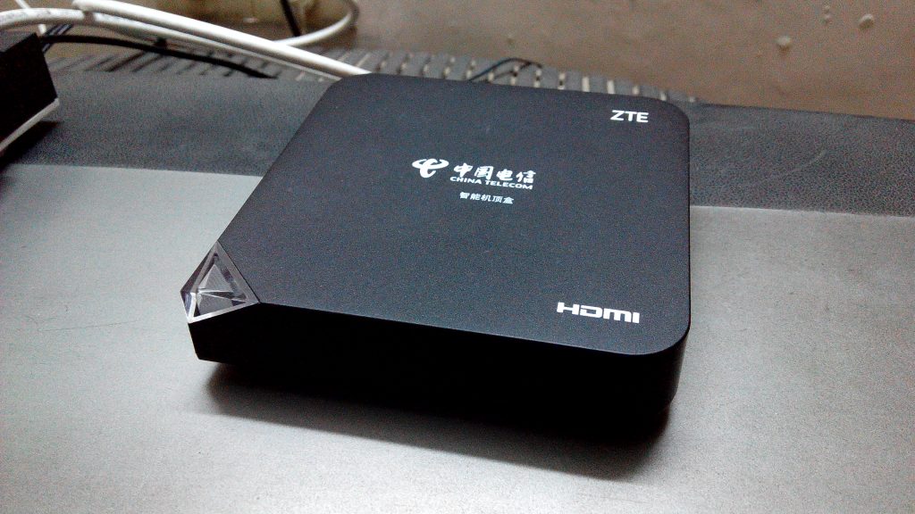 MAG IPTV set-top box on a TV stand next to a remote control, ready to purchase a MAG box